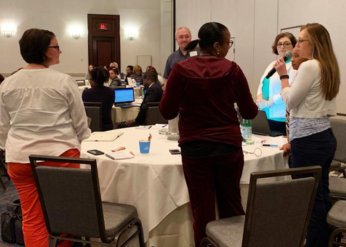 Small group of healthcare professionals discussing compliance topics during an interactive workshop activity